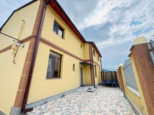 a yellow house with a driveway next to a building at Miracle View Dilijan in Dilijan