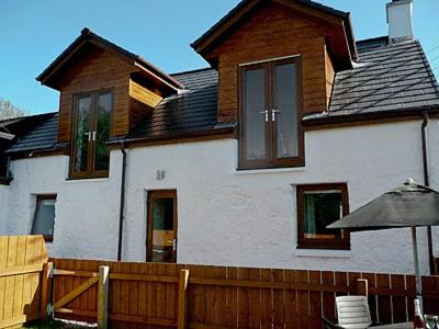 a house with a wooden fence in front of it at Blackmill Cottage in Taynuilt