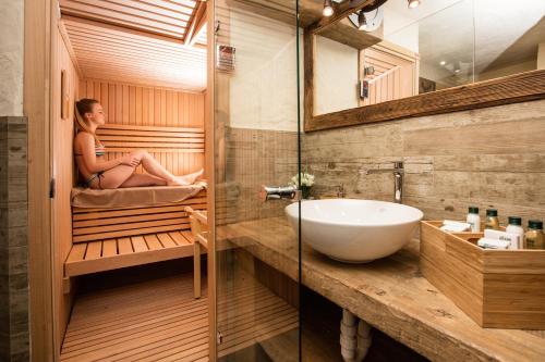 a woman sitting in a sauna with a bath tub at Chalet Charm in Livigno