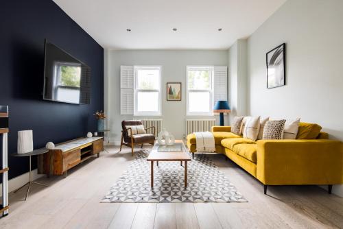 a living room with a yellow couch and a table at Exceptional 2 Bed Flat near Dulwich Park in London