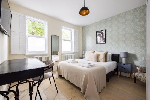 a bedroom with a bed and a desk and a piano at Exceptional 2 Bed Flat near Dulwich Park in London