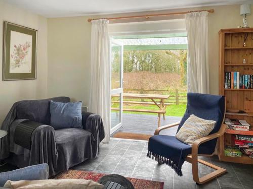 a living room with a couch and a chair and a sliding glass door at Beachside in Llanstephan