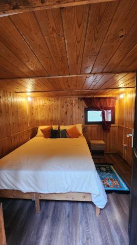 a bedroom with a bed in a wooden cabin at Cabana Pinolera in Boga