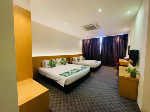 a hotel room with two beds and a tv at Melaka City Hotel in Malacca
