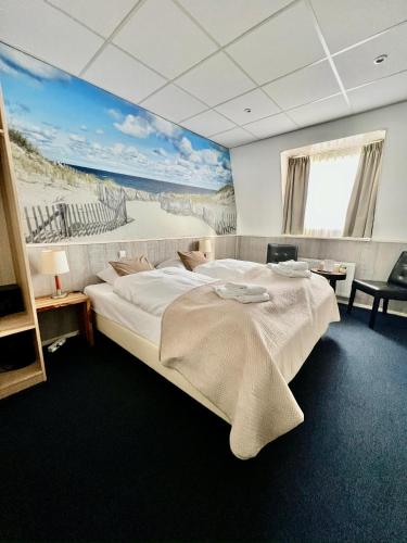a bedroom with a large bed with a painting on the wall at SEA YOU Hotel Noordwijk in Noordwijk aan Zee