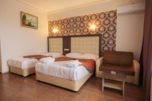 a hotel room with two beds and a chair at Divaisib Termal Resort Hotel & Spa in Kozaklı