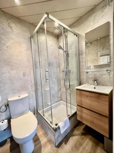 a bathroom with a shower and a toilet and a sink at SEA YOU Hotel Noordwijk in Noordwijk aan Zee