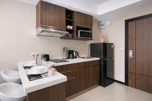 a kitchen with wooden cabinets and a black refrigerator at KAI Condo 1BR Pool View NBC Nai Harn in Rawai Beach