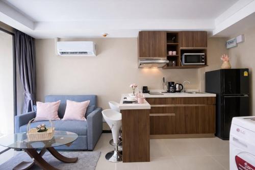a small living room with a blue couch and a kitchen at KAI Condo 1BR Pool View NBC Nai Harn in Rawai Beach