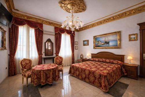 a bedroom with a bed and two chairs and a chandelier at Euro Hotel Iglesias in Iglesias
