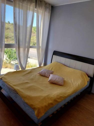 a bedroom with a bed with two pillows and a window at Апартамент Лана 2 in Byala