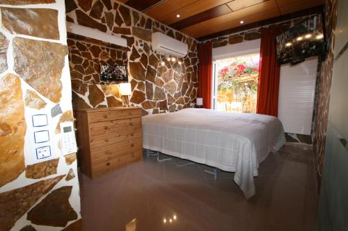 a bedroom with a bed and a stone wall at Villa Brownies in Els Poblets