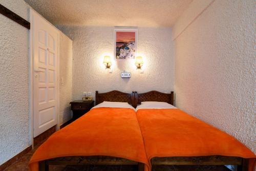 a bedroom with a bed with an orange blanket on it at Hotel Porto Perissa in Perissa
