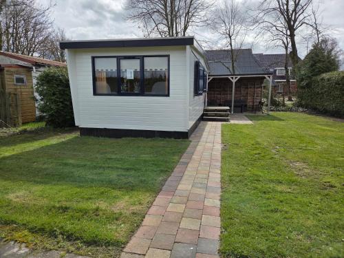a small white house with a window on a yard at De Greidefûgel in Westergeest