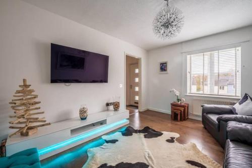 a living room with a couch and a tv at 55 Incline Way - Saundersfoot Coastal Retreat with Patio & Parking in Pembrokeshire