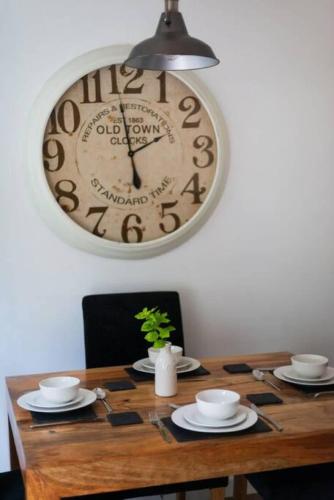 a clock hanging on a wall above a wooden table at 55 Incline Way - Saundersfoot Coastal Retreat with Patio & Parking in Pembrokeshire
