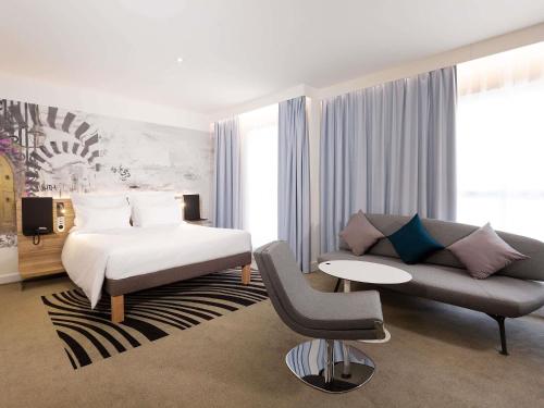a bedroom with a bed and a couch and a chair at Novotel Tunis Lac in Tunis