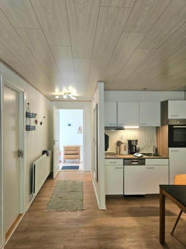 a kitchen with white cabinets and a table in it at Drømmehus Ferienwohnungen in Nørre Nebel