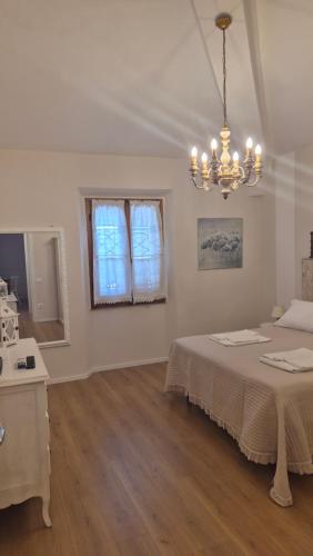 a white bedroom with a bed and a chandelier at La Perla del Boccaccio in Certaldo