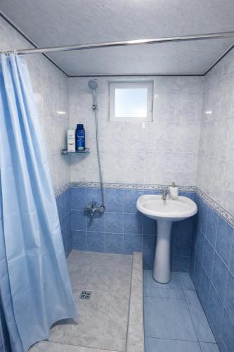 a blue tiled bathroom with a sink and a shower at Sole Family Guesthouse in Samarkand