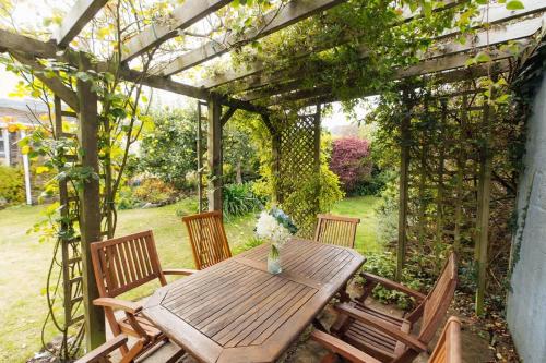 a wooden table and chairs under a pergola at Charming Upper Solva Cottage by Beaches and Harbour in Solva
