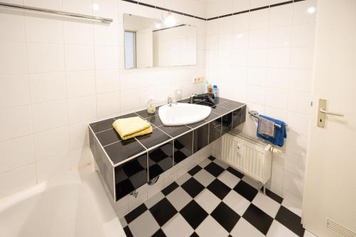 a bathroom with a sink and a black and white checkered floor at Appartement Denis in Chemnitz