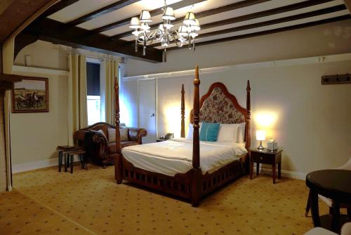 a bedroom with a bed and a chandelier at The Tudor Hotel in Harrow