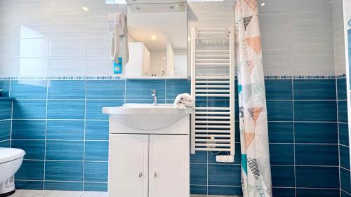 a bathroom with a sink and a toilet and blue tiles at Le Nid Des Grands Geais in Le Crotoy
