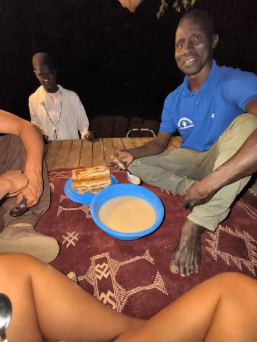 a group of people sitting around a table with a plate of food at Ibel dans le pays Bassaris in Kédougou