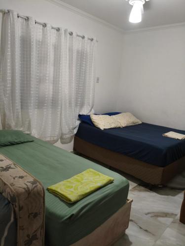 a bedroom with two beds and a window at Cantinho da Lu em apt inteiro 1km da praia in Bertioga