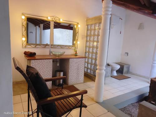 a bathroom with a vanity with a mirror and a chair at WG Villa Wathurugama in Kannimahara