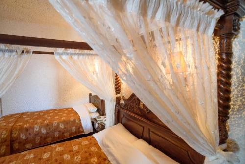 a bedroom with a canopy bed with white curtains at Hotel Porto Perissa in Perissa