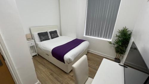 a small white room with a bed and a window at Sangha Hall - Private Ensuite Rooms with Shared Kitchen in Leicester