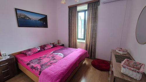 a bedroom with a pink bed and a window at Apartment Capt Seferovic 2 in Donji Morinj