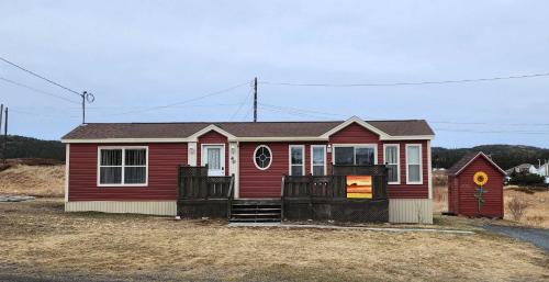 a small red house with a red door at Crimson Sky Cottage in Twillingate