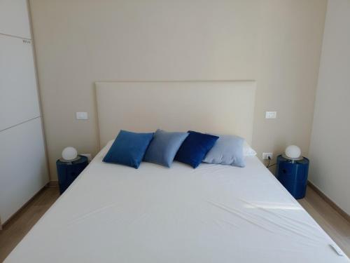 a bedroom with a large white bed with blue pillows at Riccio di Mare in Lacona