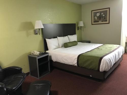 a hotel room with a bed and a chair at Southern Inn Minden in Minden