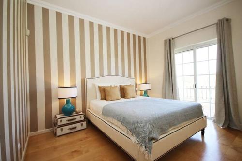 a bedroom with a bed with two lamps and a window at Formosa Villas in Quinta do Lago