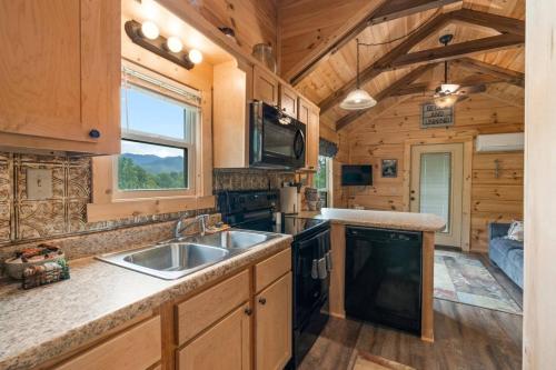 a kitchen with a sink and a stove at Smoky Mountain Mist, Tiny House, Custom Log Cabin in Bryson City