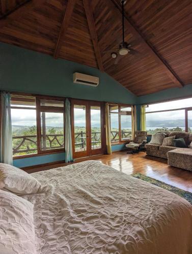 a bedroom with a large bed and some windows at Villa Siempre Aventura in Nuevo Arenal
