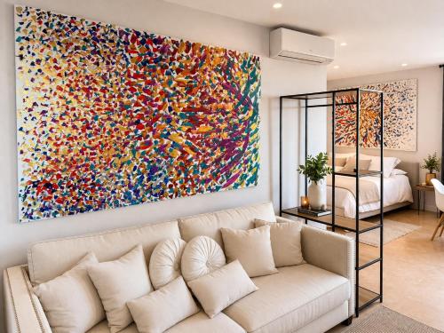 a living room with a white couch in front of a large painting at Alta Luminara Boutique Residence Sea View Terraces Marbella Hills in Benahavís