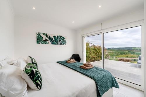 a bedroom with a bed and a large window at Villa Adão Lobo in Cadaval