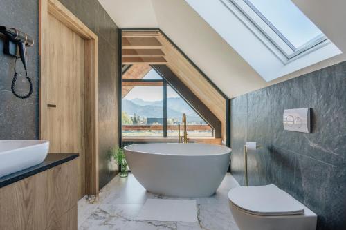 a bathroom with a large bath tub and a window at Wierchy View - bespoke villas in Kościelisko