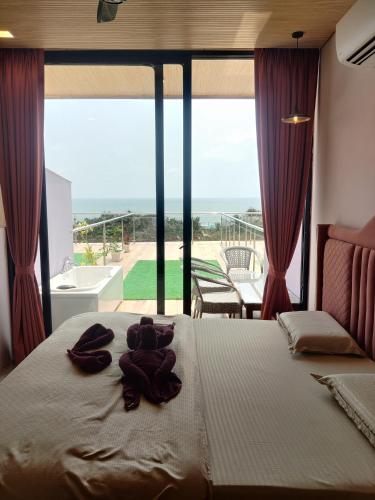 a bedroom with a large bed with a large window at Coco 7 Beach Resort in Mandrem