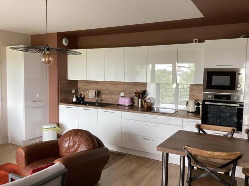 una cocina con armarios blancos y una mesa con un sofá en Les flots de Cancale, en Cancale