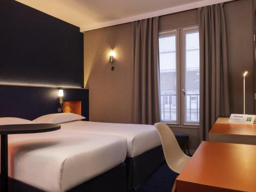 a hotel room with two beds and a table at ibis Styles Bourg La Reine in Bourg-la-Reine