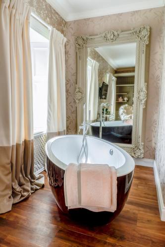 a large bath tub in a bathroom with a mirror at The Painted Cow in Beattock