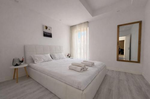 a white bedroom with a large bed with a mirror at Jupiter Suite #6people in Ştefăneştii de Sus