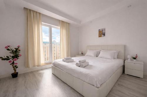 a white bedroom with a large bed with towels on it at Jupiter Suite #6people in Ştefăneştii de Sus