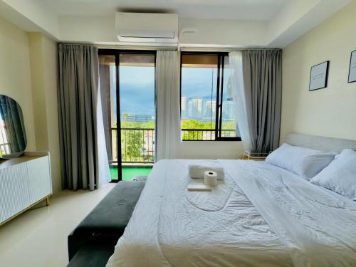 a bedroom with a large bed with a large window at Suite Escape Mactan , condo with balcony near Mactan Newtown and Mactan Airport in Mactan
